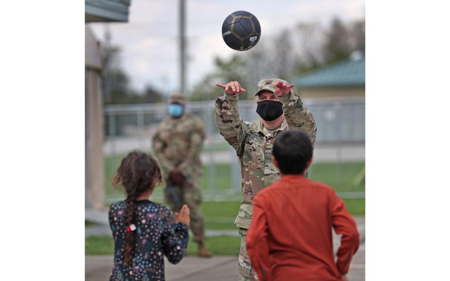 Children play volleyball with soldiers and others outside an Operation Allies Welcome community building Thursday, Oct. 14, 2021, at Camp Atterbury in Edinburgh, Ind.