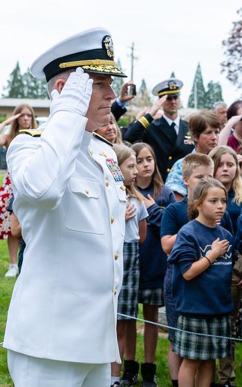 Rear Adm. Richard Brophy, chief of Naval Air Training, salutes the passing casket of retired Lt. Cmdr. Lou Conter during Conter’s memorial service.
