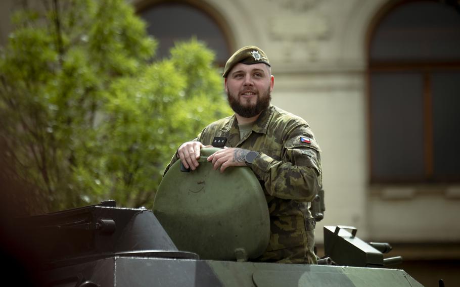 A man in uniform rides a tank.