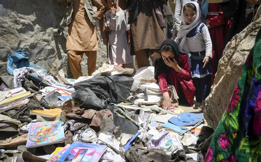 Children pick through items left behind the day after a deadly attack on the Syed Al-Shahda school in Kabul, Afghanistan, May 9, 2021. 