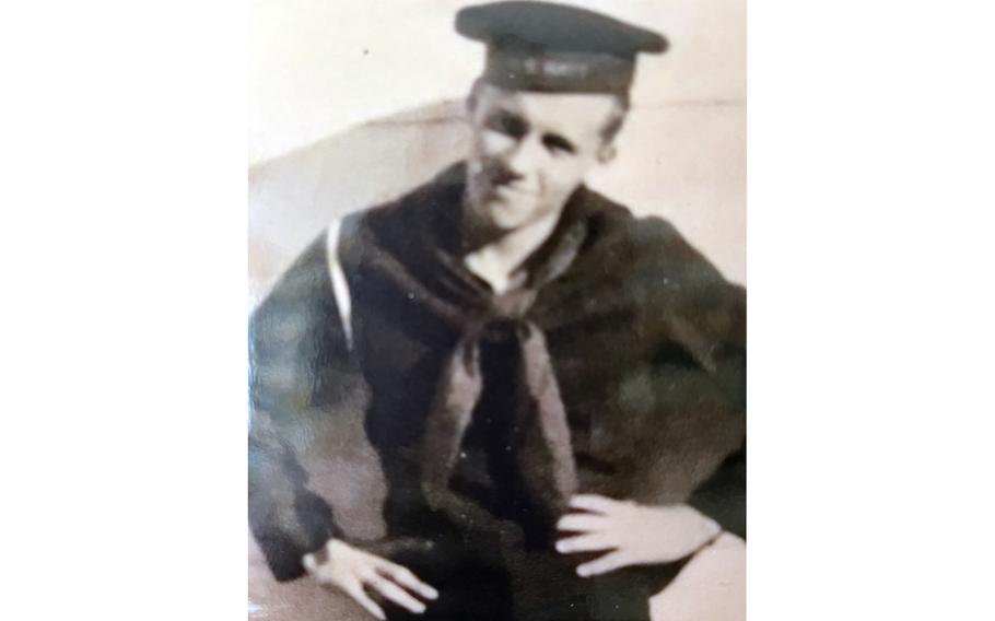 A black-and-white, 1940s-era portrait of a Navy sailor in hat and uniform posing with his hands on his hips.