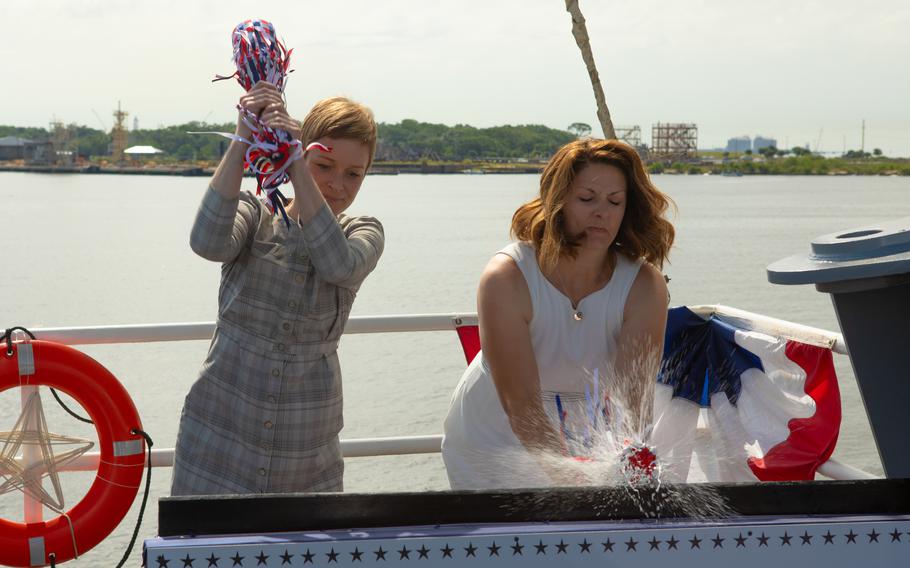 Kate Oja, left, and Shana McCool break champagne bottles as part of a christening ceremony for USS Richard M. McCool Jr. (LPD 29) in Pascagoula, Miss., June 11, 2022. Oja and McCool are the sponsors and granddaughters of Capt. Richard M. McCool Jr., a Navy officer who was awarded the Medal of Honor for his actions during the Battle of Okinawa in World War II.