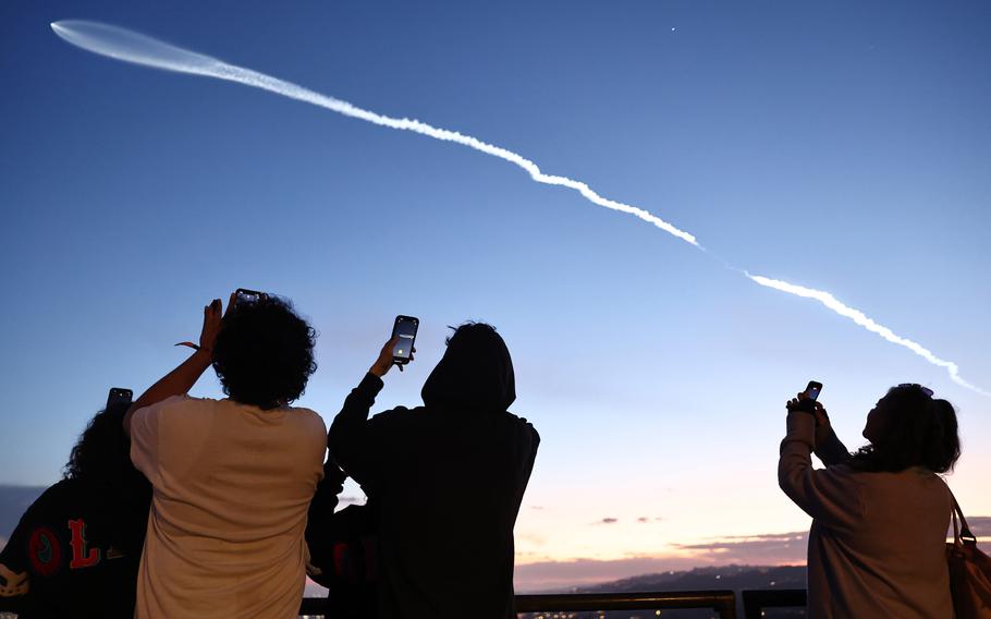 People view a SpaceX Falcon 9 rocket carrying a payload of 22 Starlink internet satellites into space after launching from Vandenberg Space Force Base, as seen from Los Angeles on March 18, 2024.