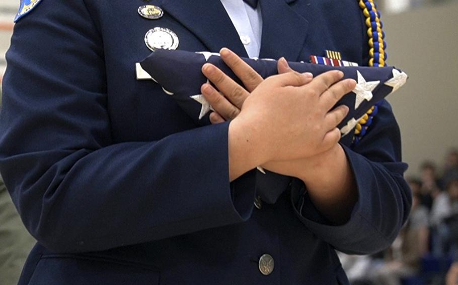 A member of the Junior Reserve Officer Training Corps carries an American flag flown in Syria during a ceremony at the high school on Yokota Air Base, Japan, Thursday, May 11, 2023.