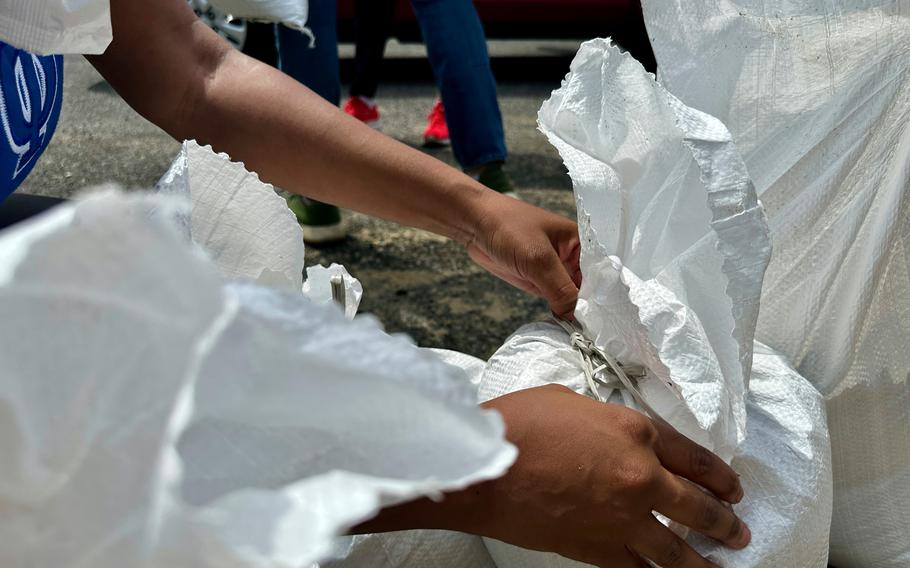 Hands reach in to tie a sandbag.