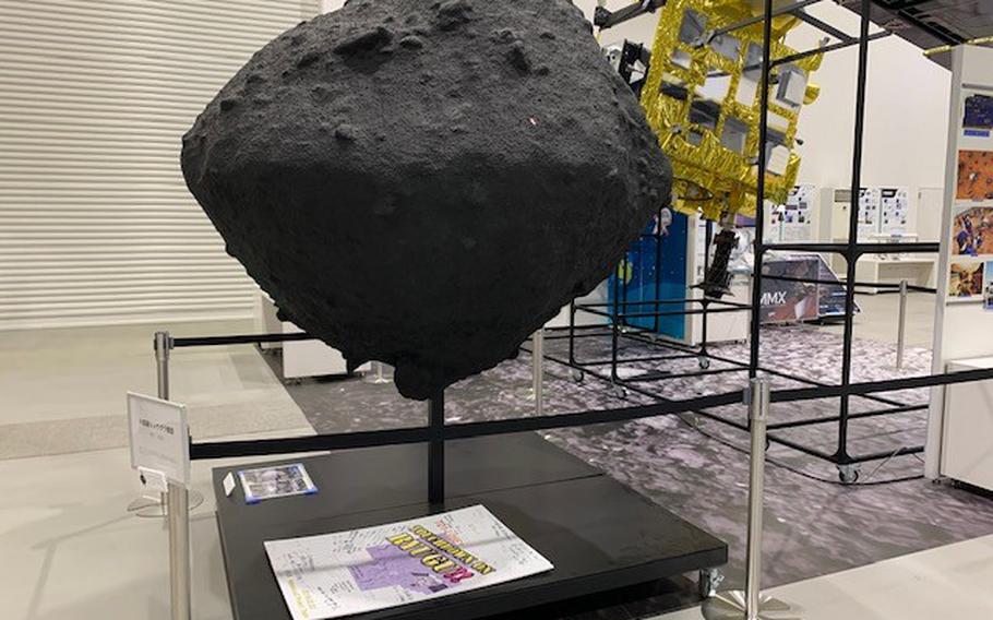 An exhibit at JAXA’s campus in Sagamihara, Japan, has full-sized models of various rockets and spacecraft, such as a reusable rocket, the RVT-9, and a model of the asteroid 162173 Ryugu, along with descriptions in both Japanese and English. 