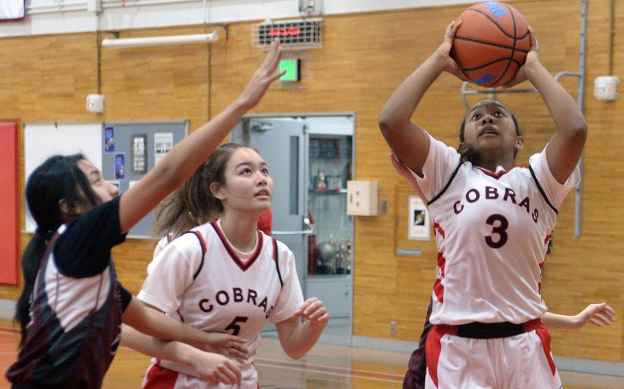 E.J. King's Moa Best puts up a shot as teammate Aileen FitzGerald watches and Matthew C. Perry's Aiya Versoza defends during Friday's DODEA-Japan basketball game. The Cobras won 55-4.