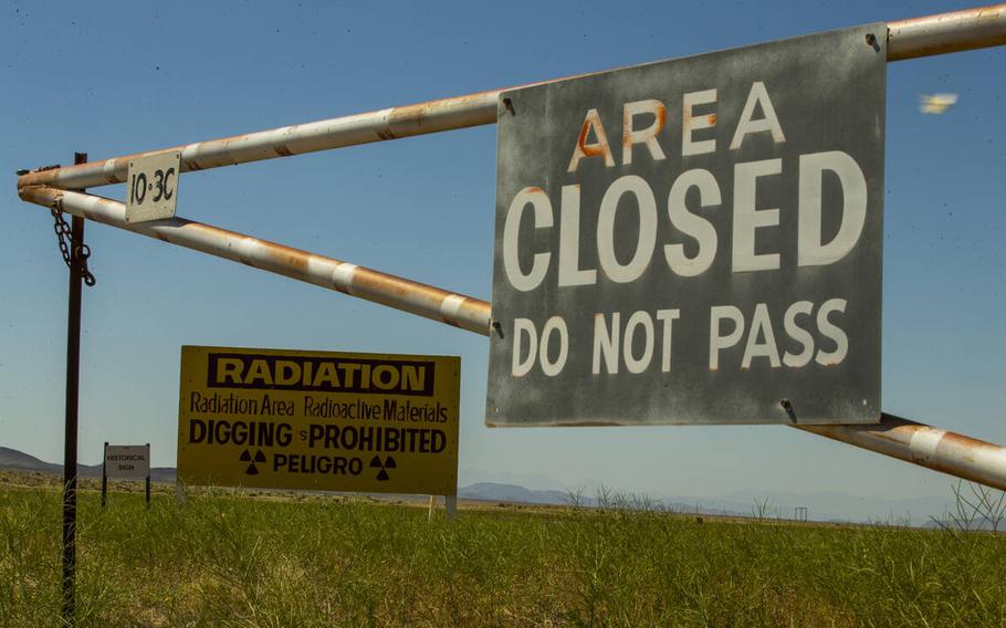 A sign reading “AREA CLOSED/DO NOT PASS”  on a grassy field.