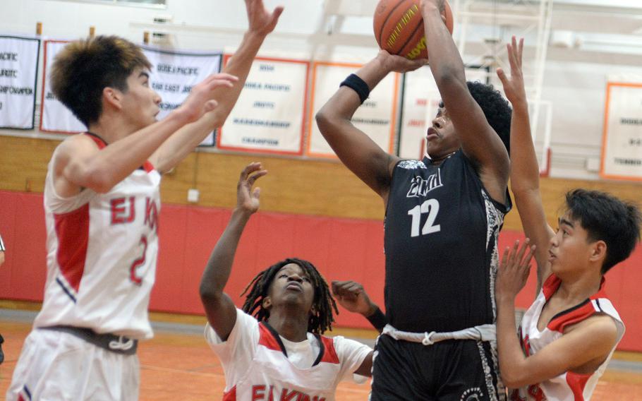 Zama's Amari King shoots between E.J. King defenders Nolan FitzGerald, Jeremy Phillips and Jared Hernandez during Friday's DODEA-Japan boys basketball season-opening game. The Trojans won 57-54.