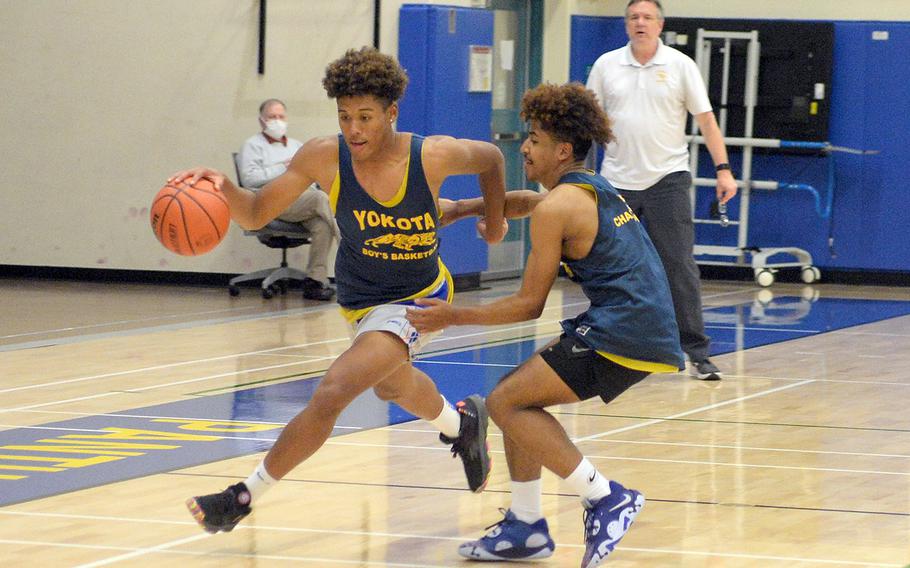 Yokota senior Zemon Davis dribbles against senior teammate Marcus Woods under coach Dan Galvin's watchful eye. The two players are among nine seniors on the Panthers boys basketball team.