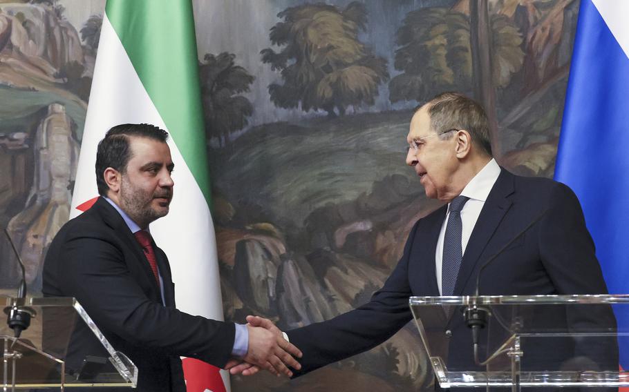 Russian Foreign Minister Sergey Lavrov, right, and Syrian Foreign Minister Asaad Hassan al-Shibani, left, shake hands after a joint news conference following their meeting in Moscow, Russia.