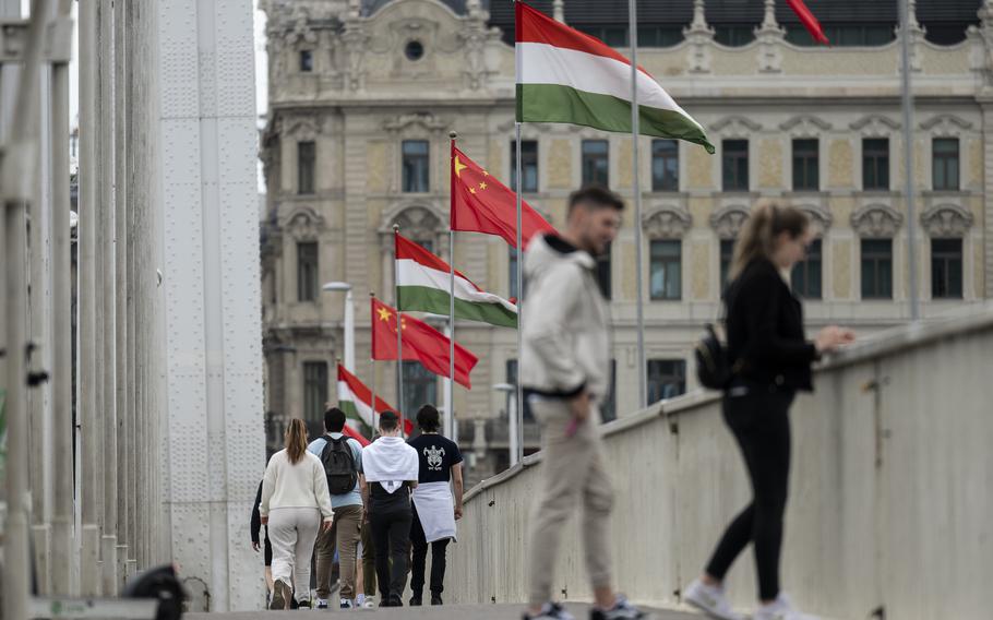 Tourists walk next to Chinese national flag placed on the Elisabeth Bridge in Budapest, Hungary, Wednesday, May 8, 2024. 