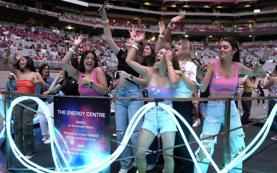 Concertgoers dance during Coldplay’s Music of the Spheres world tour May 12, 2022, at State Farm Stadium in Glendale, Ariz. The band has included energy-storing stationary bikes to their latest world tour, encouraging fans to help power the show as part of a push to make the tour more environmentally friendly. 