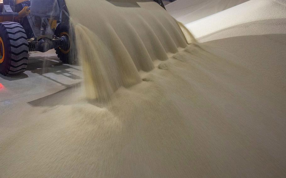 A worker operates a front-end loader to move granules of phosphate fertilizer in a storage warehouse at a fertilizer plant, in Cherepovets, Russia. 