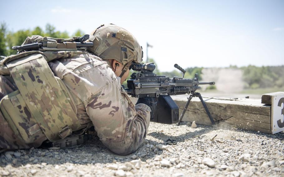 A soldier lies prone and fires a light machine gun.