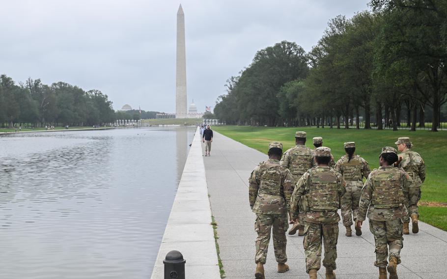D.C. National Guard soldiers walk by the reflecting pool at the National Mall in Washington on Aug. 18, 2025. 