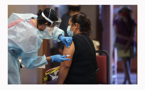 A nurse prepares to administer a flu vaccination shot to a woman at a free clinic held at a local library on Oct. 14, 2020, in Lakewood, California. 