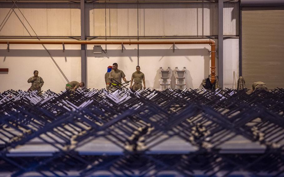 Service members assemble cots for Afghan evacuees Aug. 22, 2021, at Al Udeid Air Base, Qatar. 