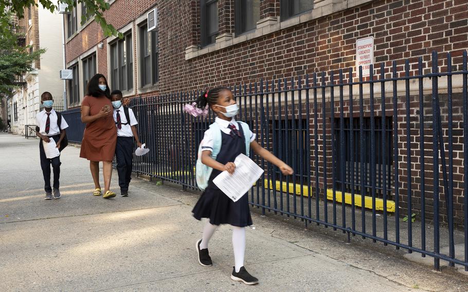 A girl leads her mother and brothers as they arrive at Brooklyn's PS 245, Monday, Sept. 13, 2021, in New York. Classroom doors are swinging open for about a million New York City public school students in the nation's largest experiment of in-person learning during the coronavirus pandemic.