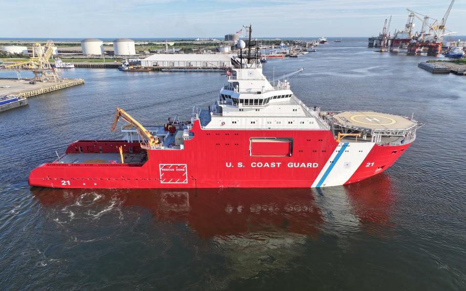 A Coast Guard cutter transits a shipyard.