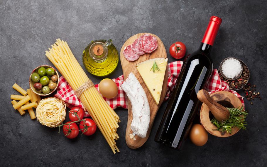 Italian cuisine food ingredients. Pasta, cheese, salami, olives and wine. Top view flat lay on stone table