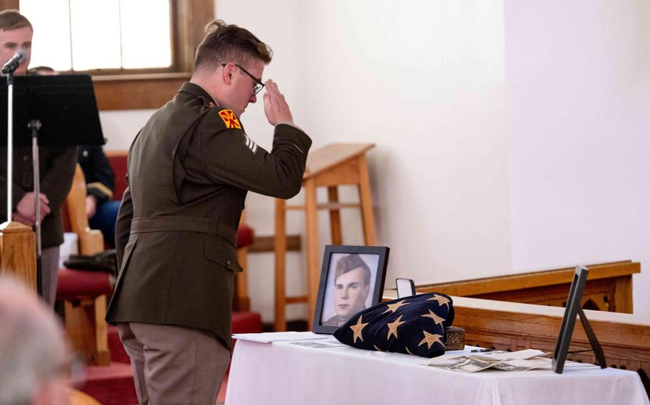 Martin stands at a table that holds a flag and photos of his great uncle.