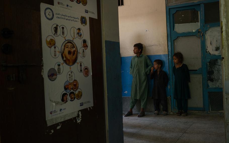 Children stand near a poster promoting polio vaccination at the main clinic in Afghanistan’s Achin district on Nov. 12, 2023. 