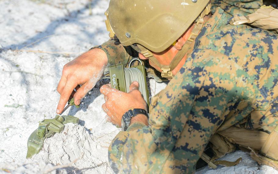 A Marine infantry student places a claymore mine during training at Camp Lejeune, N.C., on Aug. 27, 2021. The students were practicing an ambush during an initial infantry training pilot program meant to drastically change the way the Corps trains its infantrymen. The pilot program expands infantry training from nine to 14 weeks and places Marines in 14-person squads under a single instructor.