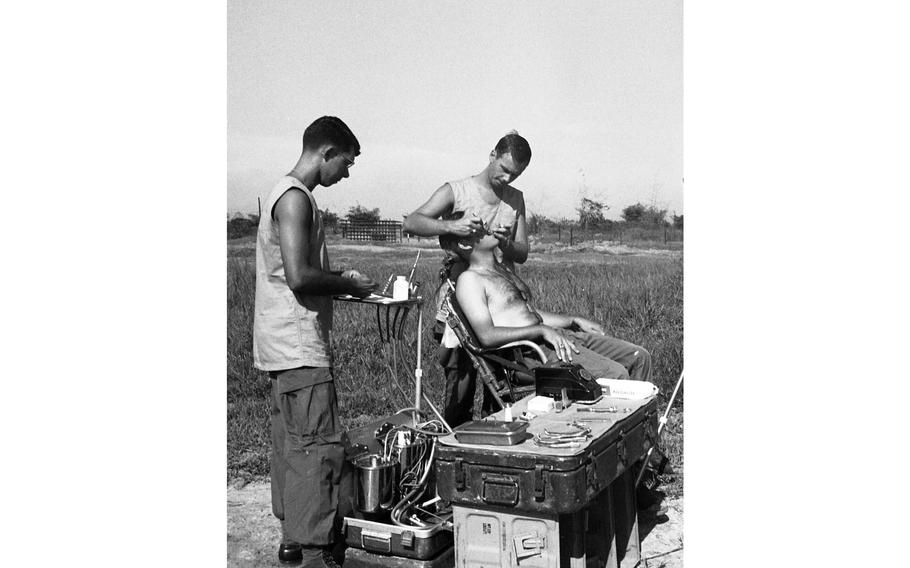 Three times a month Capt. and Dr. Earle Yeamans, the Big Red One’s travelling dentist, and his assistant Spc. 5 Richard Ackley, hoist their 600-pound portable dentist’s office aboard a helicopter and head for the boonies. They stay in the area three or four days, examining every man in the unit and scheduling appointments.