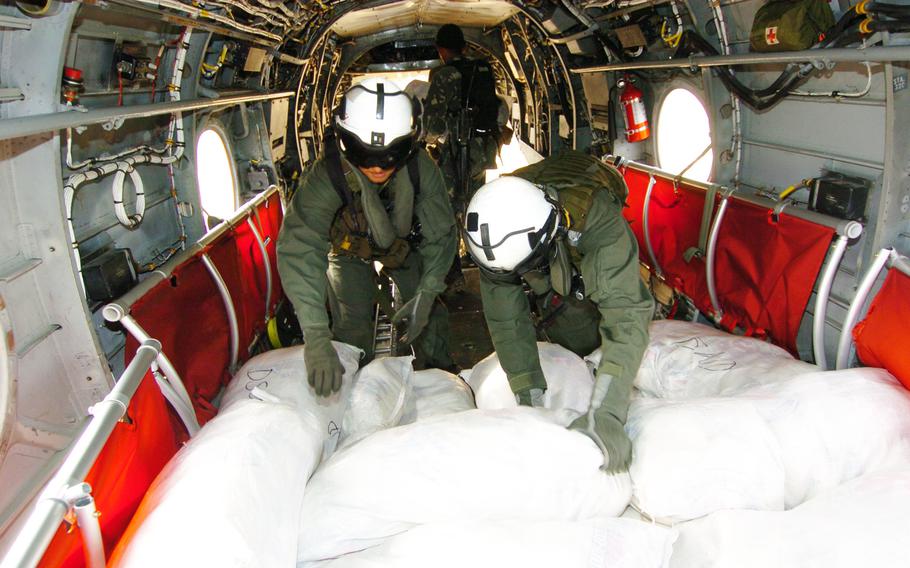 Marine helicopter aircrewmen Cpl. Eric Hernandez, left, and Lance Cpl. Chad Thompson, right, move bags of relief aid destined for storm-ravaged communities in the Philippines.
