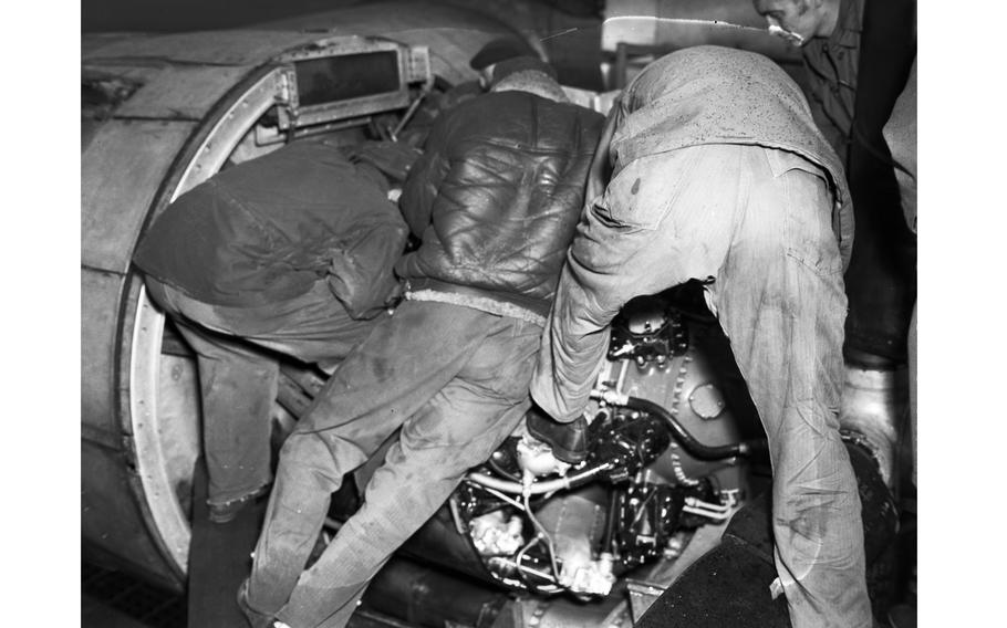A crew checks an aircraft engine