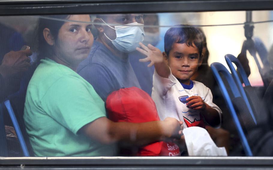 A young migrant who traveled from Texas to Union Station in Chicago waves as his family waits to depart to temporary housing on Friday, Sept. 9, 2022.