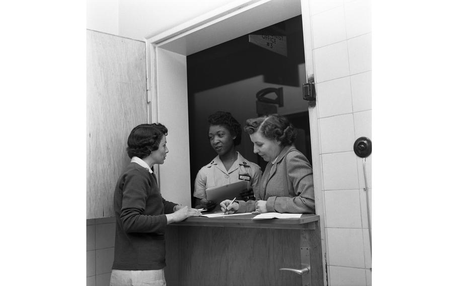 Ms. A. Baker (center) and two unidentified women stand at the 97th General Hospital Maternity Ward’s Receptionist Office. 