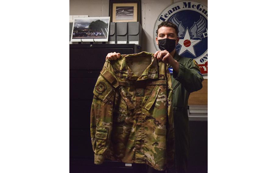 Airman First Class Nicolas Baron, 305th Air Mobility Wing Loadmaster, holds his blouse for the last time before donating it to the National History Museum of the U.S. Air Force at Joint Base McGuire-Dix-Lakehurst, N.J., Oct. 12, 2021.