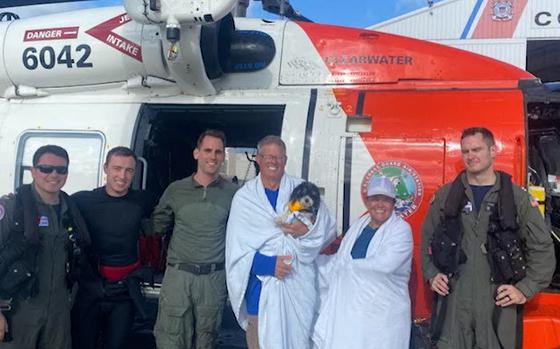 Robert and Heather Cook, with their dog, Bandit, pose with the Coast Guard members who saved them Saturday, about 90 miles off the shore of Hernando Beach, Fla.