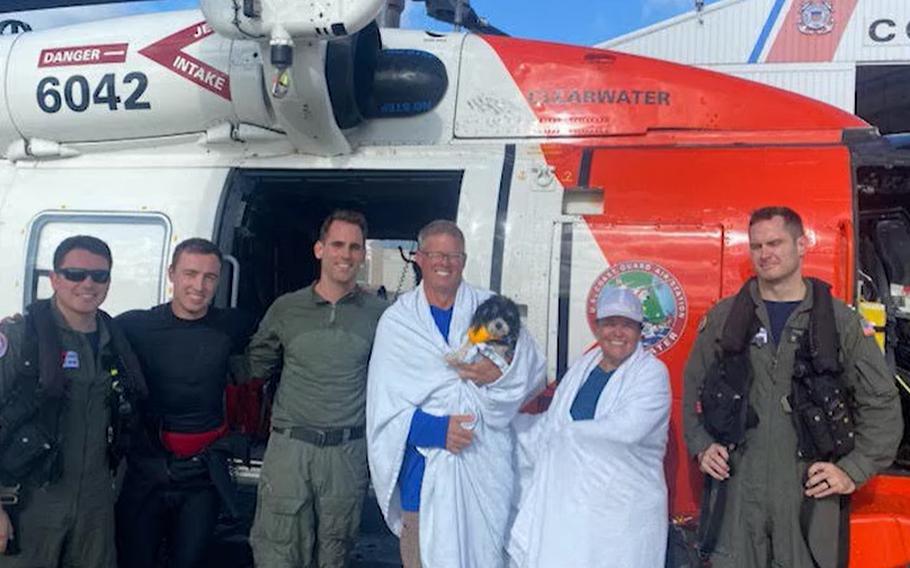 Robert and Heather Cook, with their dog, Bandit, pose with the Coast Guard members who saved them Saturday, about 90 miles off the shore of Hernando Beach, Fla.