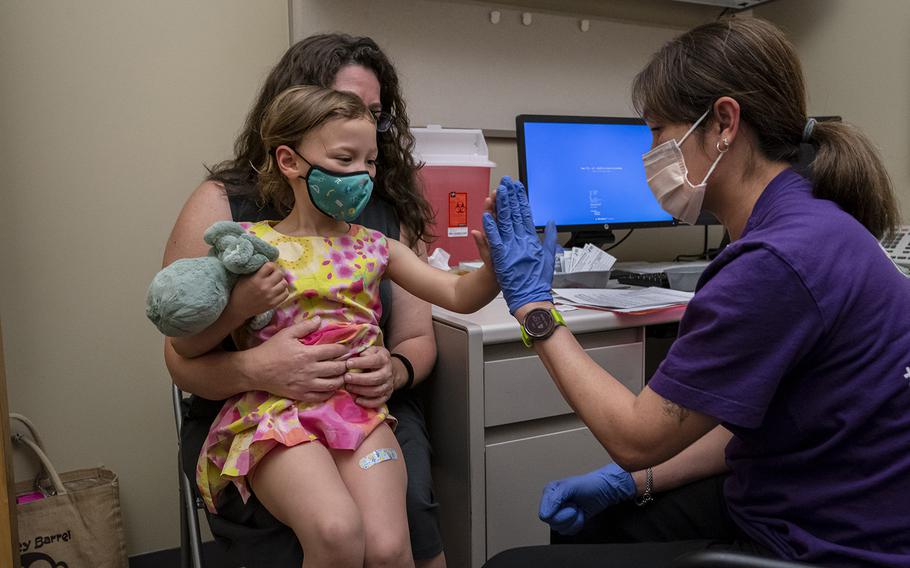 Nora Burlingame, 3, sits on the lap of her mother, Dina Burlingame, and gets a high five from nurse Luann Majeed after receiving her first dose of the Pfizer COVID-19 vaccination at UW Medical Center-Roosevelt on June 21, 2022, in Seattle. 