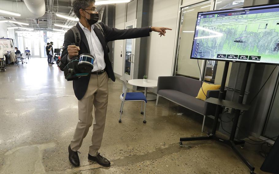 University of Pennsylvania Dean for the School of Engineering & Applied Science Vijay Kumar points to a television screen using the ExynPak, a portable, real-time 3D mapping solution with survey grade accuracy. Kumar was leading a tour of the Penn Engineering and Applied Sciences of General Robotics, Automation, Sensing and Perception Lab (GRASP) at the Pennovation Center on May 23, 2022.