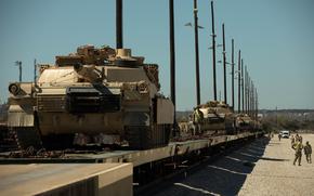 Tanks ride on a line of rail cars.