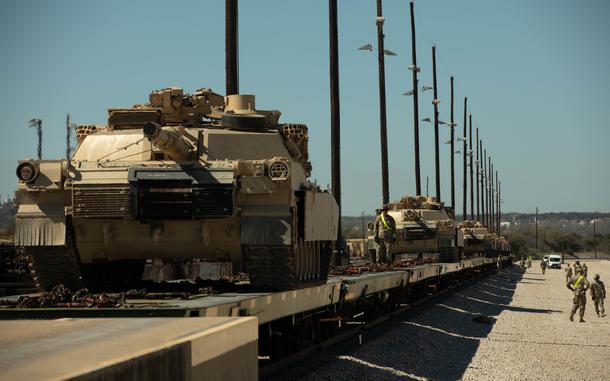 Tanks ride on a line of rail cars.