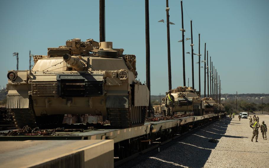 Tanks ride on a line of railcars.