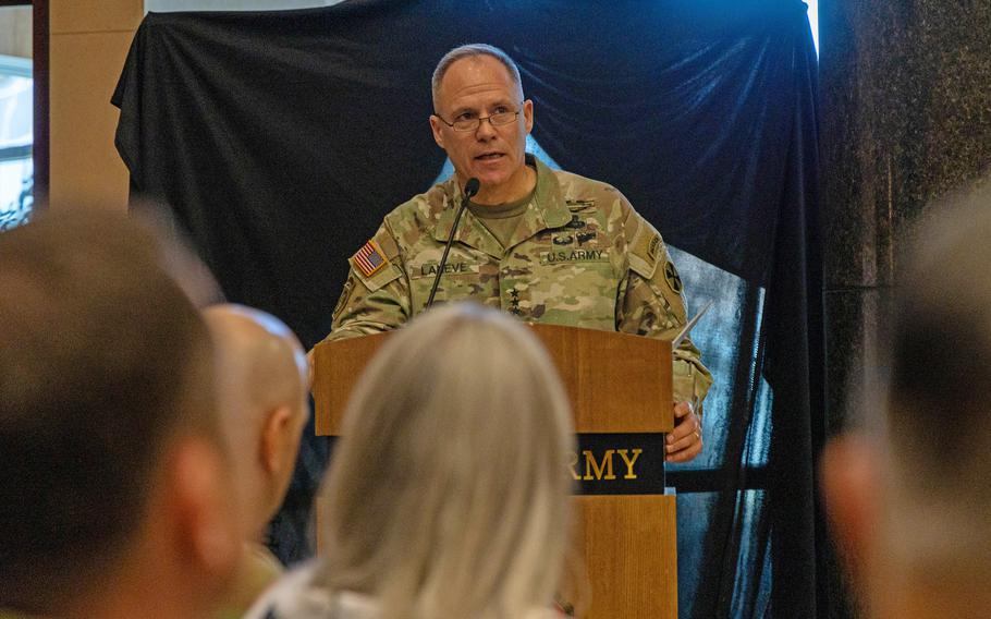 Christopher LaNeve, wearing an Army uniform, stands at a podium and speaks to an audience.