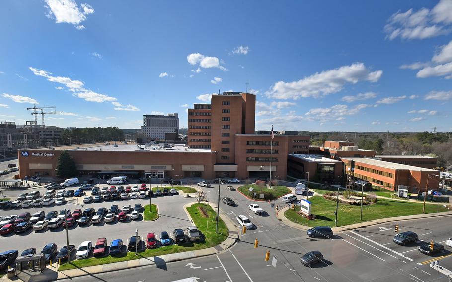 An aerial view of a hospital complex with a parking lot full of cars outside.