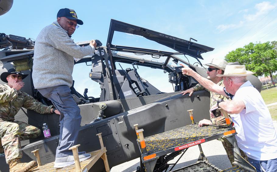 Man climbs up on a helicopter as a soldier assists him and two other men look on.