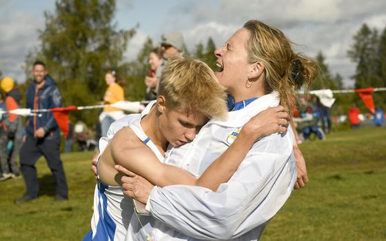 Wiesbaden junior Luke Jones collapses in the arms of his jubilant coach Stephanie Escalante after breaking the course record with a time of 16 minutes, 8.57 at the boys DODEA-Europe cross country championship race Oct. 21, 2023, in Baumholder, Germany.