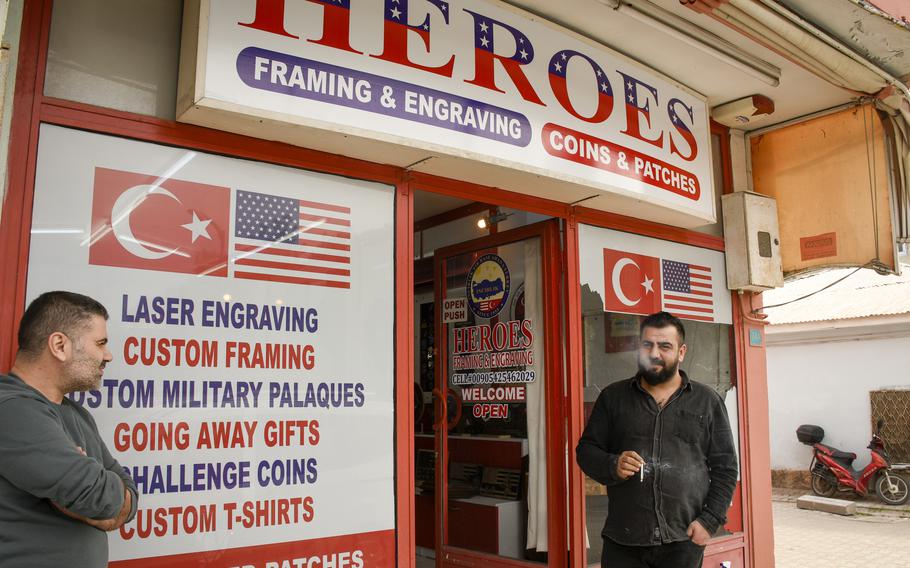 Hakan Bindal, right, smokes in front of his engraving shop as he talks to his friend, Murat Sertekin, just outside the gate of Incirlik Air Base in southern Turkey on Feb. 25, 2023. 