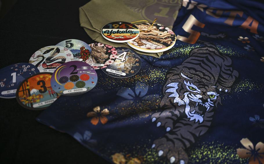 Colorful car sticker decals are laid out on a tablecloth featuring a tiger.