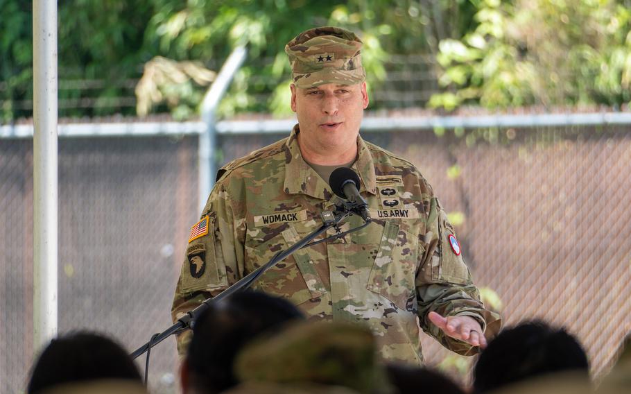 Maj. Gen. Dave Womack stands at a podium in uniform to speak during an outdoor ceremony.