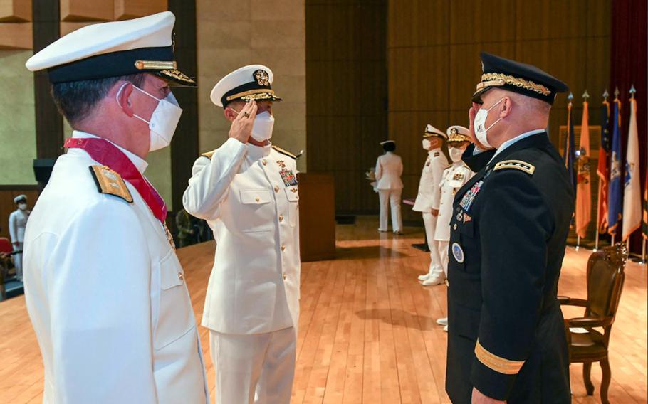 Rear Adm. Mark Schafer, center, salutes the head of U.S. Forces Korea, Army Gen. Paul LaCamera, after taking command of Naval Forces Korea in Busan, South Korea, Sept. 29, 2021. The outgoing commander, Rear Adm. Michael “Buzz” Donnelly, stands at left. 