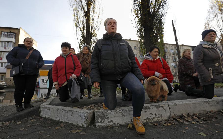 On Nov. 9, 2022, residents of Borodyanka, Ukraine, kneel as the casket carrying Oleksii Kozlenko, 32, proceeds down Tsentralna Street during a procession to the cemetery. He was killed on the frontline in Bakhmut, Ukraine, leaving his wife and children behind.